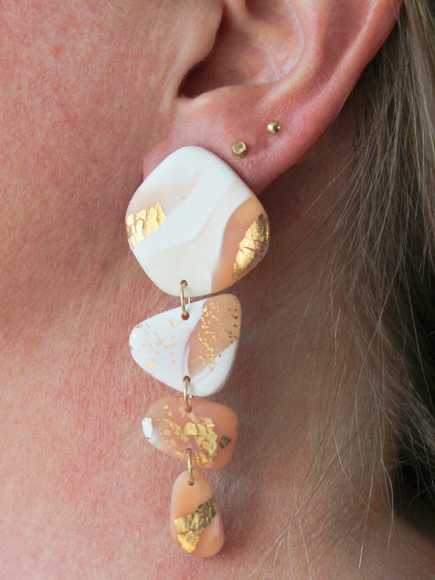 Alma Rosa bold gold leaf earrings with layered design featuring soft pastel colors and gold accents