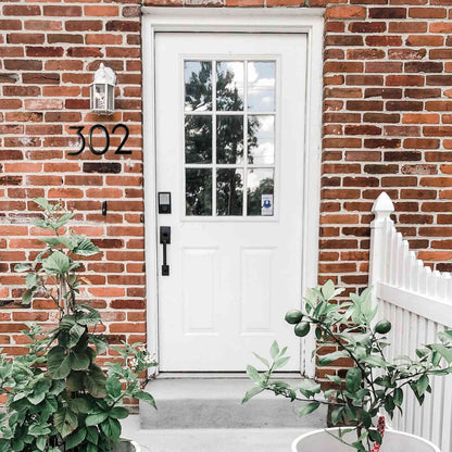 Black aluminum number 5 on a brick wall next to a white door for stylish home decor