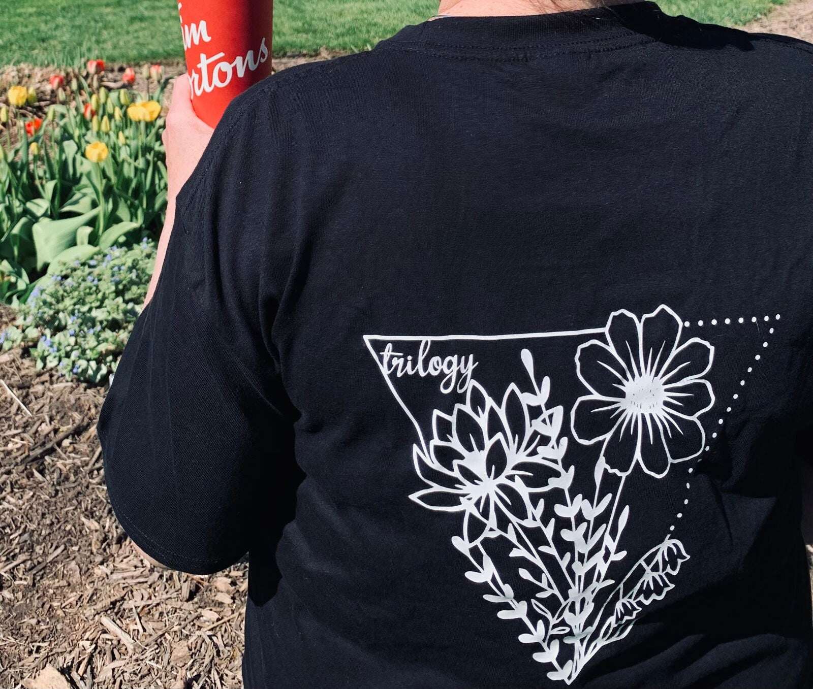 Black floral t-shirt Canada featuring white floral design on the back showcased in an outdoor setting