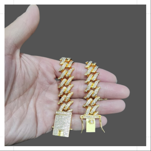 Gold Cuban link bracelet featuring a bold design and sparkling accents held in a hand