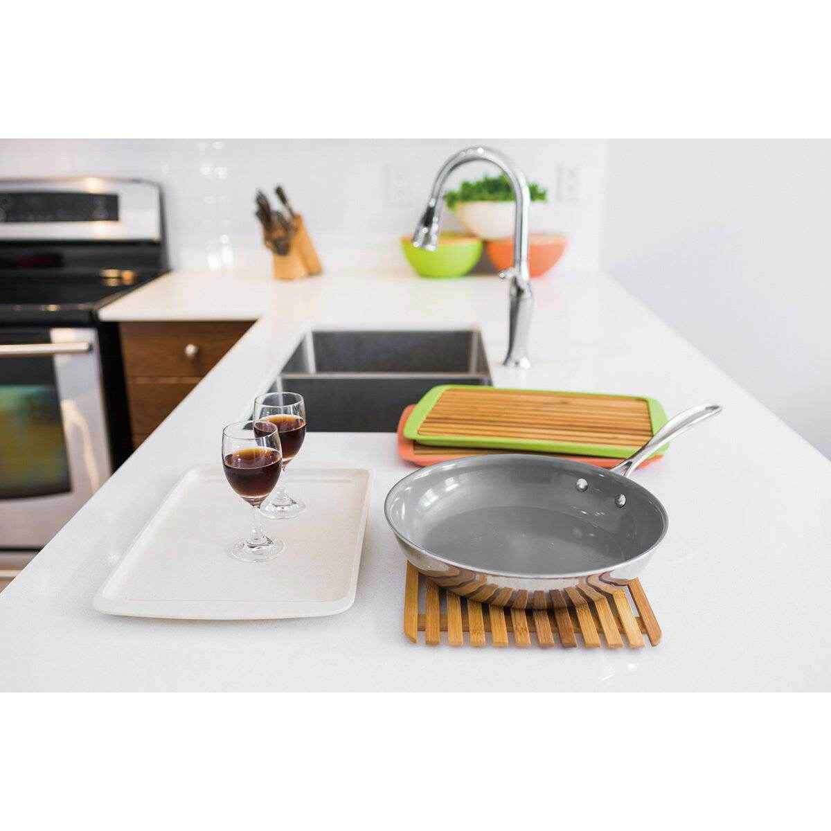 Large bamboo serving board alongside kitchen utensils and glasses for entertaining and serving meals