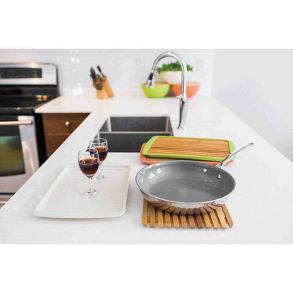Large bamboo serving board alongside kitchen utensils and glasses for entertaining and serving meals