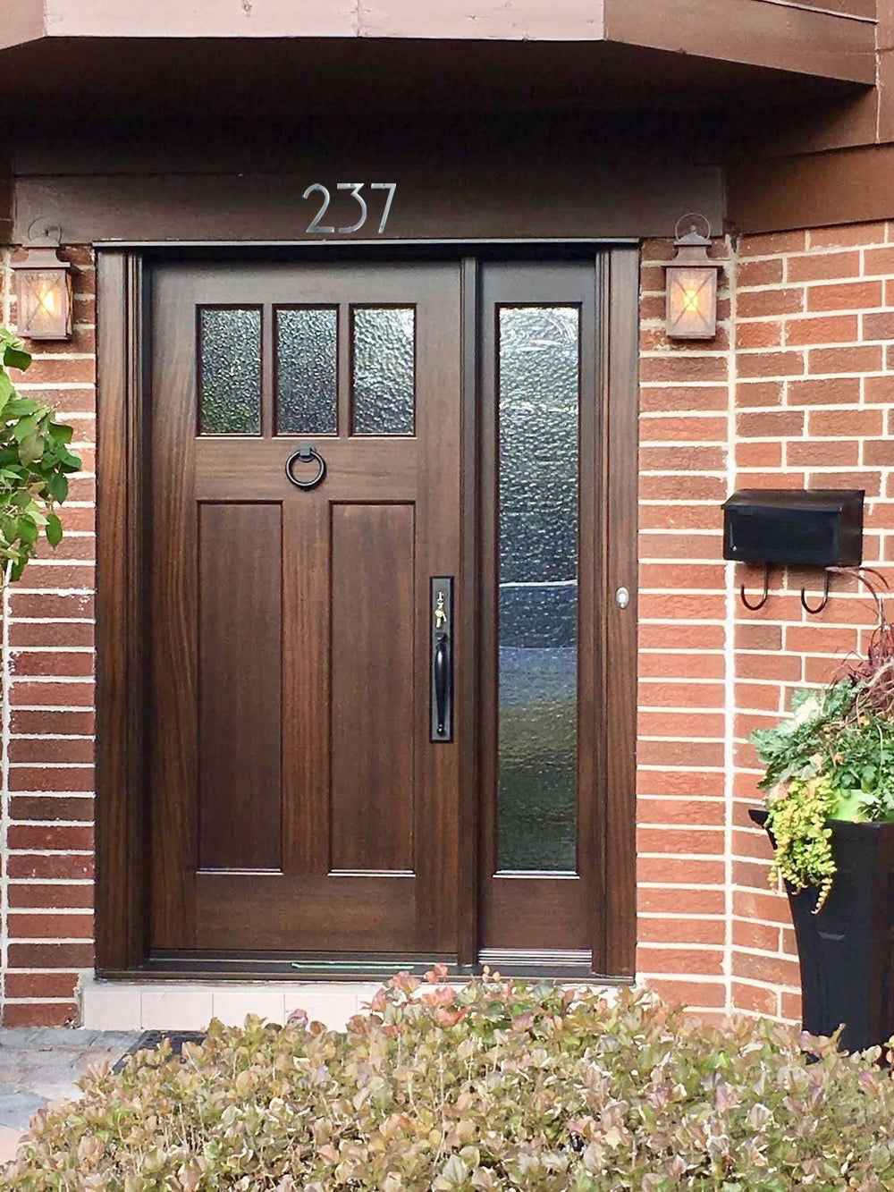 Elegant brown wooden front door with decorative glass panels and a silver house number 3 on top